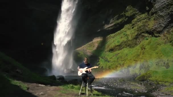 Mannen Som Spelar Gitarr Framför Ett Vackert Vattenfall Island Slowmo — Stockvideo