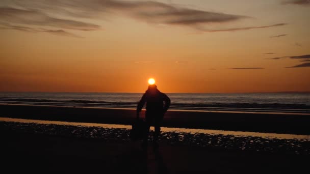 日没時に砂浜でギターを持って走る男 ソニーA7Iiiから美しく ムーディなショット — ストック動画