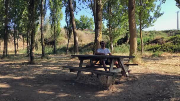 森の中の木のテーブルに座っている男 — ストック動画