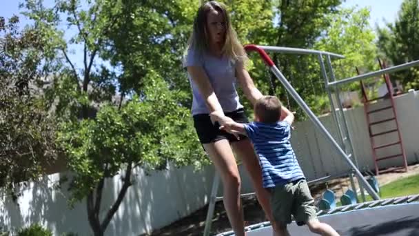 若い女の子と若い男の子のスローモーションショット遊びやジャンプ一緒に上のバウンシートランポリンで彼らの裏庭 — ストック動画