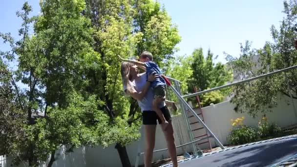 一个年轻女孩和一个年轻男孩在自家后院的蹦床上玩耍和跳跃的慢镜头 — 图库视频影像