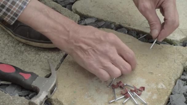 コンクリート床の上に釘フックケーブルクリップで爪を準備作業員の手 — ストック動画