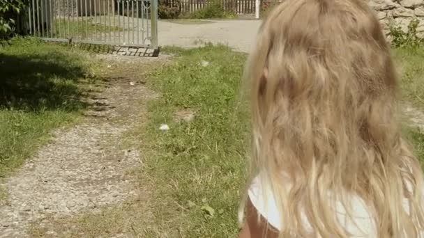 Ένα Μικρό Κορίτσι Σκύβει Και Κοιτάζει Καθώς Λευκές Πεταλούδες Χορεύουν — Αρχείο Βίντεο