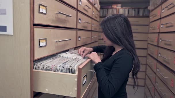音乐图书馆里的年轻女子 搜寻带有光盘的抽屉 — 图库视频影像