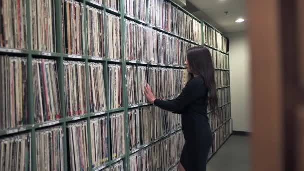 fiatal nő üzembe Phonograph Record vissza a polcra a zenei könyvtár