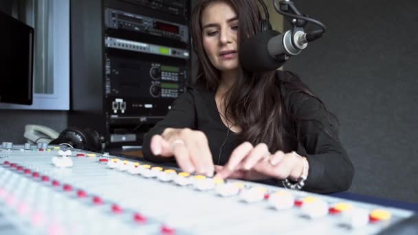 Gyönyörű fiatal nő, rádió DJ beszél a közönséggel, miközben a mixetén dolgozik
