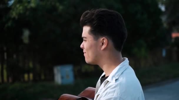 若い男性アーティストがアコースティックギターで街を歩く — ストック動画