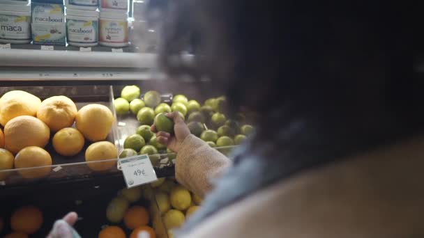 在杂货店 吸引人的年轻非洲裔美国妇女在水果蔬菜超级市场上选择带有购物袋的石灰 — 图库视频影像