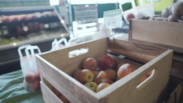 A szupermarketben: Lassú babakocsi egy doboz almával és szilvával, árakkal a vonzó élelmiszerboltban.