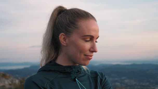 Fiatal sportos nő egy hegy tetején élvezi a kilátást a naplementében - 4K Slowmotion