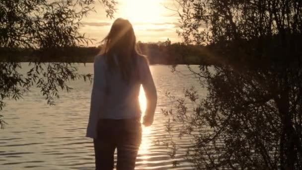 日落时分走向波涛汹涌的湖面的女性轮廓 — 图库视频影像
