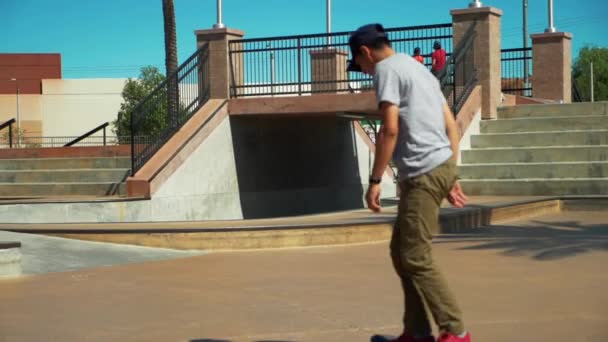 Slow Motion shot of young male Skateboarder Riding Skateboard at Skate Park performing a trick