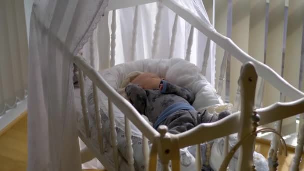 寝ている赤ん坊はベッドに寝そべっている 木製のクレードルの間で広いドリーライトショット — ストック動画
