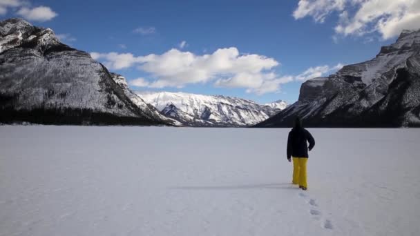 Yürüyüşçü Dağlık Bir Vadide Karla Kaplı Gölün Üzerinde Yürüyor — Stok video
