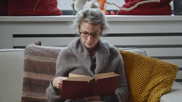 안경을 소파에 거실의 아파트에서 공부하고 독서하는 코카서스 여성에게 돌진하는 — 비디오