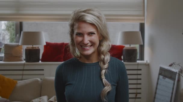 若い女性の肖像画笑顔と現代のきれいなリビングルームのアパートの家でカメラといちゃつく — ストック動画