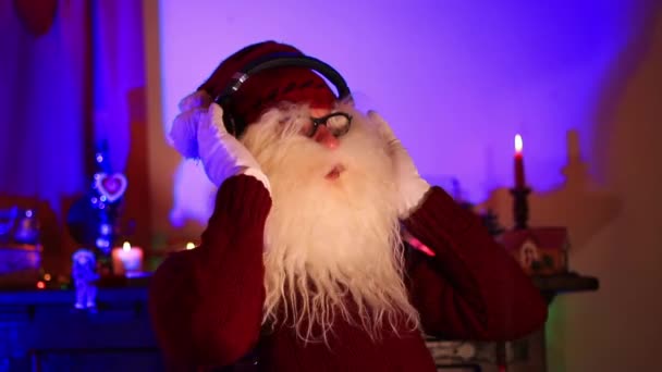 圣诞老人通过耳机听音乐 在明亮的紫色房间里跳舞 — 图库视频影像