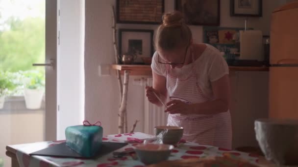 Medium Shot, rámozdul egy női pékre, aki egy pékségben dolgozik. A születésnapi torta utolsó simításait készíti elő..