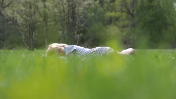 Portrét roztomilé kavkazské bezstarostné dívky ležící na trávě v parku, statický zpomalený film s mělkou hloubkou pole