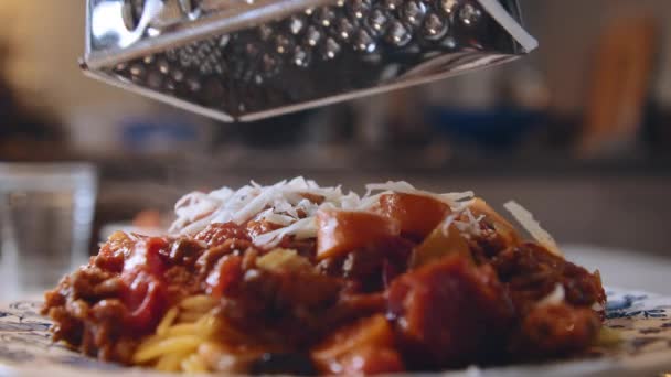 Detailní záběr čerstvého italského parmezánu strouhaného na horkých pařených špagetách s boloňskou omáčkou