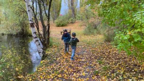 Dois Rapazes Correr Pelo Parque Beira Lago Outono Está Chovendo — Vídeo de Stock