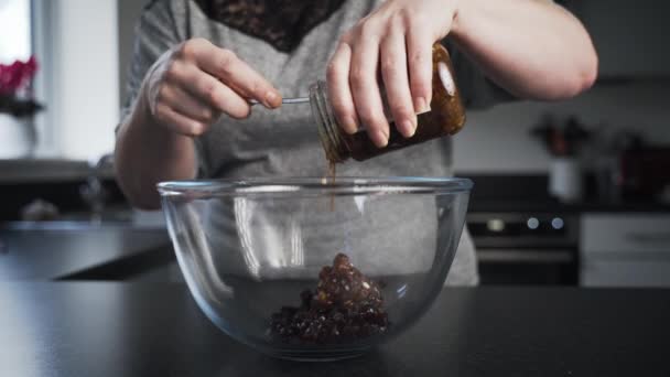ガラス瓶に詰められた粘りのあるパイをクリアミキシングボウルにスクレープする女性 女作るMineceatパイ取得準備にミックス成分で彼女のキッチン — ストック動画