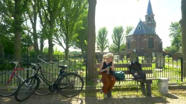 Kvinnlig Cyklist Vilar Bänk Och Dricker Lite Vatten Framför Kyrka — Stockvideo