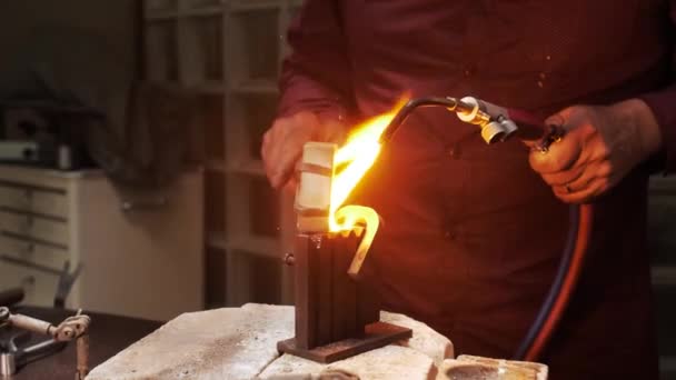 Nalévání roztaveného zlata do kovové formy při zahřívání plynovou hořákem