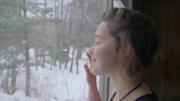 Cámara Lenta Chica Mirando Nieve Caer Por Ventana Luego Sonreír — Vídeos de Stock