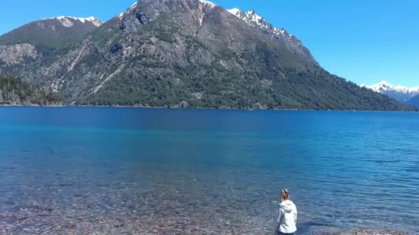 女の少女は バリローチェのエスコンディド湖とナウエル ハピ湖の空中撮影を岩の上を歩く湖畔に近づく アルゼンチンのパタゴニア — ストック動画