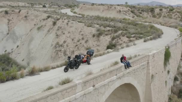 Пара Мотоциклистов Отдыхает Мосту Путешествуя Велосипедах Европе Право Воздушное Панорамирование — стоковое видео