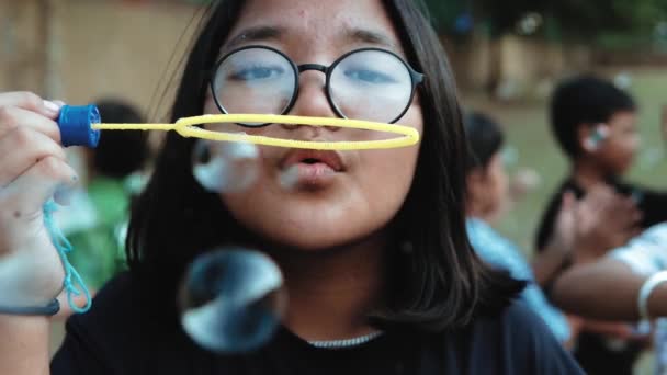 Nettes Kleines Mädchen Bläst Seifenblasen Auf Einem Spielplatz Voller Kinder — Stockvideo