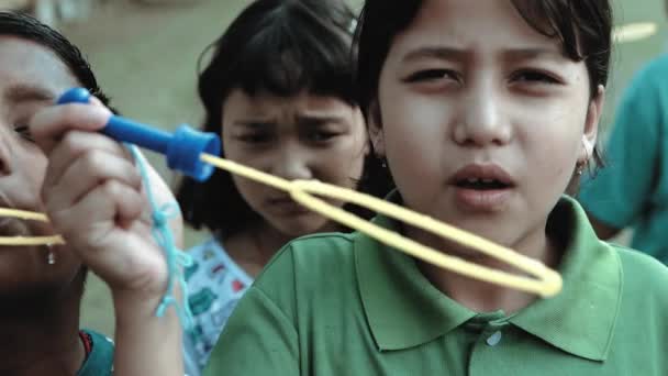 Zpomalený film 4k záběry dívky foukání mýdlové bubliny obklopen s ostatními dětmi na hřišti 