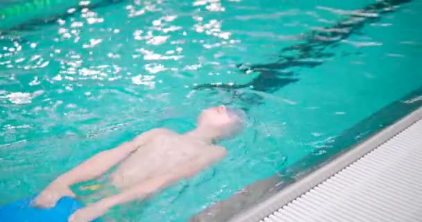 Jongen Doet Backstrokes Overdekt Zwembad Terwijl Het Houden Van Een — Stockvideo