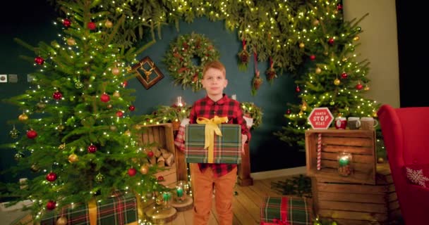Αγόρι Κρατάει Χριστουγεννιάτικο Δώρο Του Και Χοροπηδάει Πάνω Κάτω Από — Αρχείο Βίντεο