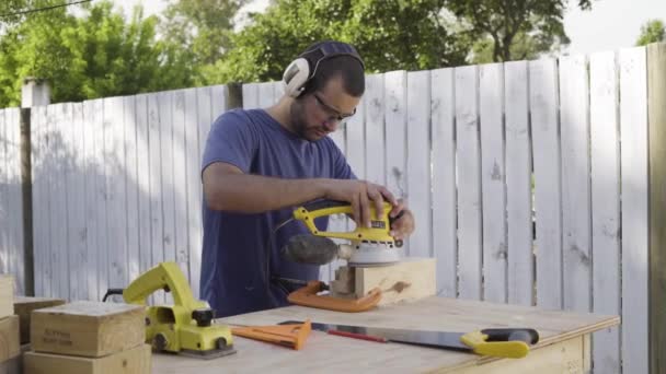 Stolarz Używa Szlifierki Orbitalnej Deskach Drewnianych Miejscu Budowy Nosząc Jednocześnie — Wideo stockowe