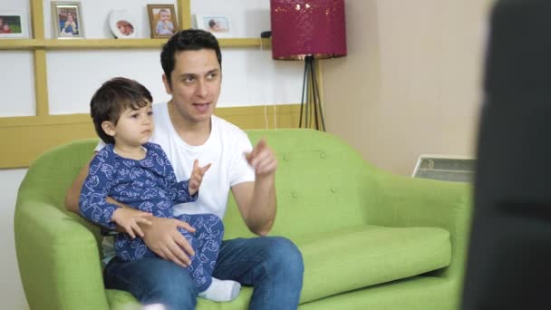 Homem Senta Sofá Com Seu Filho Menor Assiste — Vídeo de Stock