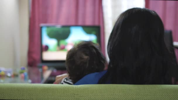 妈妈和她的小男孩坐在沙发上看卡通片 男孩没有脸就从后面开枪 — 图库视频影像