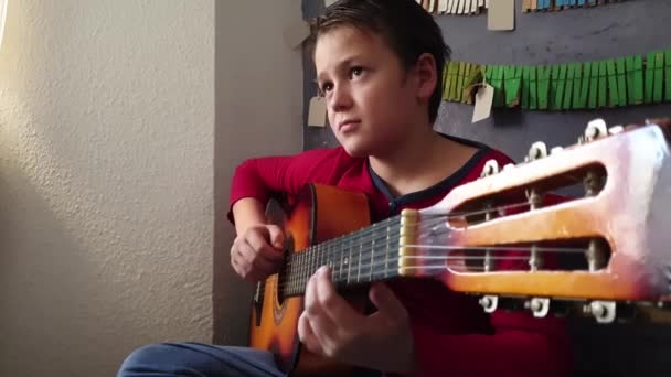 坐在沙发上练习弹吉他的男孩 — 图库视频影像