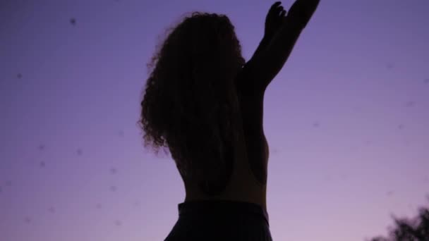 A Beautiful Woman Dancing To The Bats Flying In The Purple Sky - Raising Her Hands And Arms In A Circling Motion