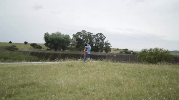 緑の牧草地で抱き合うロマンチックな若いカップル — ストック動画