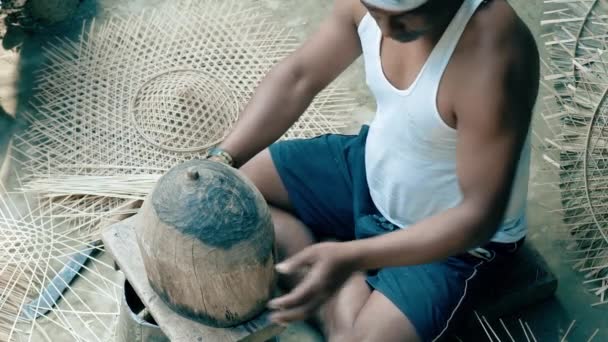 Muž, který si bere dřevěnou plíseň a dává na ni bambusový klobouk, aby získal správný tvar pro hlavu