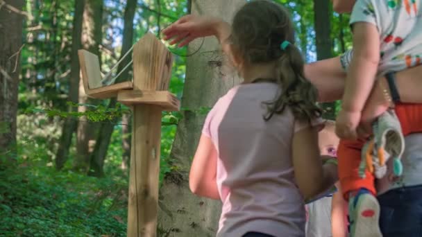 子供たちと一緒に森を探索し 楽しい方法で自然を体験するために開発されたゲームをプレイする家族 — ストック動画