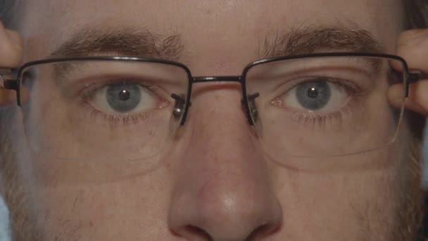 カメラを覗き込む青い目のペアからメガネが取り除かれるのを閉じる — ストック動画