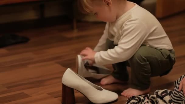 Uma Criança Gordinha Bonito Fixando Sapatos Salto Branco Chão Madeira — Vídeo de Stock