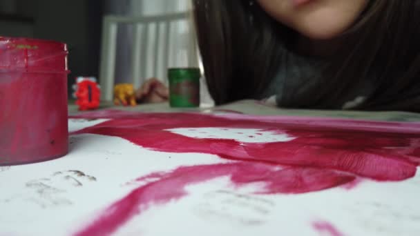 Közelkép Gyermek csinál Szépművészeti házi feladat. Lány festés fehér papírra ecsettel vörös vízszínnel