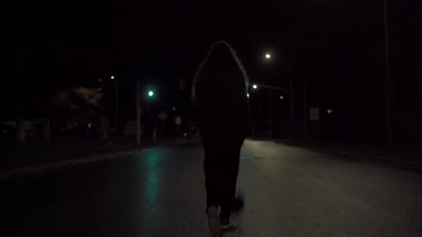 若いです女の子で黒セータードリブルバスケットボールダウンザ黄色ラインのぬれた街の通りに夜にヘッドライトで距離 — ストック動画