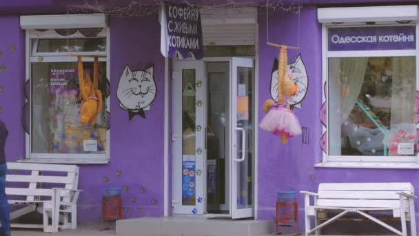 A purple storefront with a cat image at the door. People walk by.