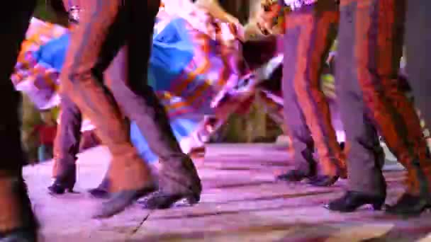 Closeup of men stomping their boots as women twirl their dresses in a Mexican folk dance.