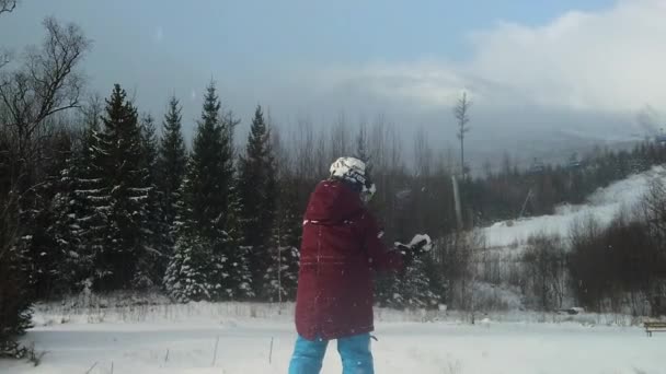 子供は肩の上のフレークの秋に白いフィールドに雪のボールをスローします — ストック動画